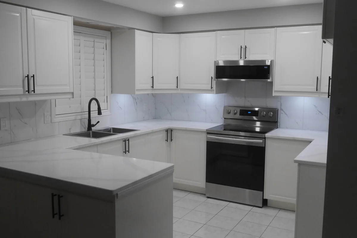 Completed kitchen renovation with white cabinets and dark hardware